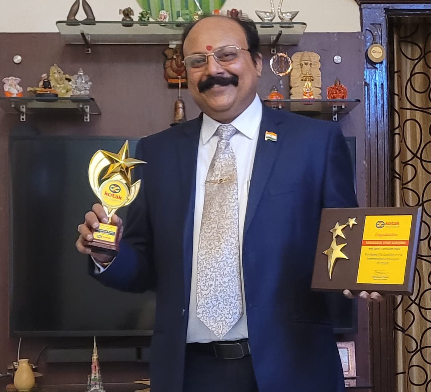 Basavaraj Vijay Karjinni holding the Kotak Life star trophy and the FSB Qualifier plaque for the H2 International Convention.