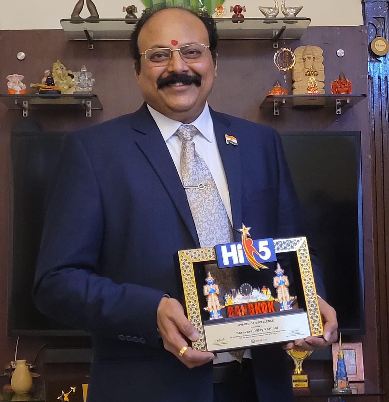 Basavaraj Vijay Karjinni holding the Kotak Life Hi 5 Award of Excellence memento from the Bangkok international convention.