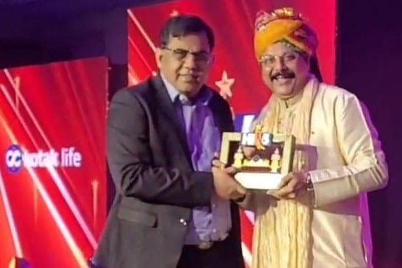 Basavaraj Vijay Karjinni receiving the Kotak Life Hi 5 Bangkok memento on stage from a Kotak Life executive.
