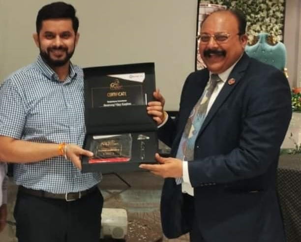 Basavaraj Vijay Karjinni receiving the Kotak Life Premier Agency certificate and memento box from a Kotak Life manager.