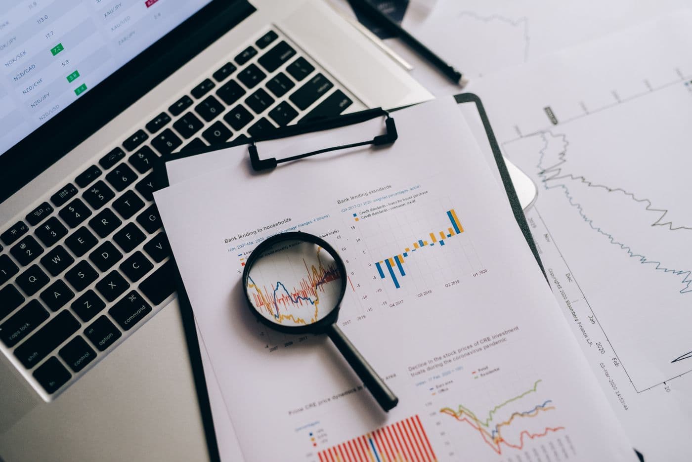 A magnifying glass over printed market charts