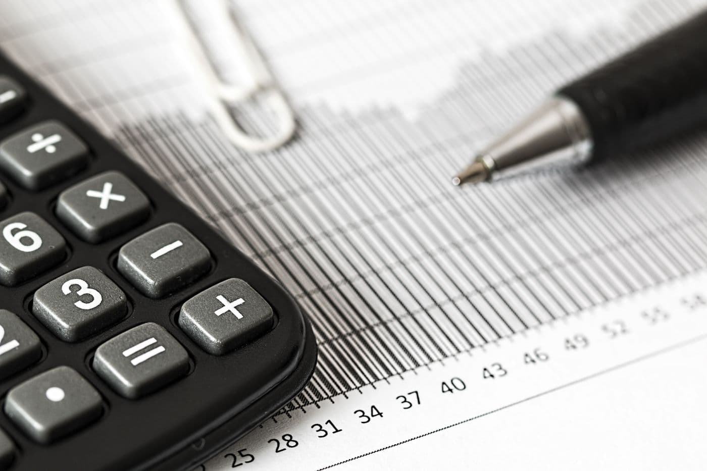 A calculator and pen resting on a printed financial chart
